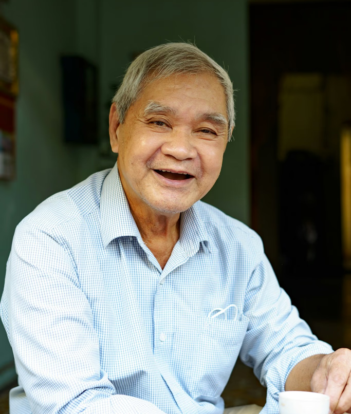 A smiling older adult enjoying a cup of tea